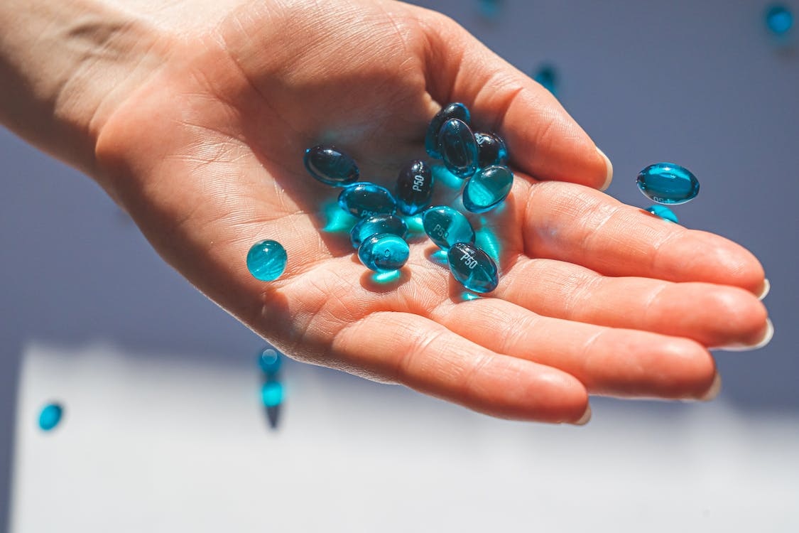 Person Holding Blue Weight Loss Pills Supplements